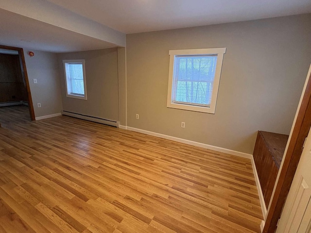 spare room with baseboard heating and light hardwood / wood-style flooring