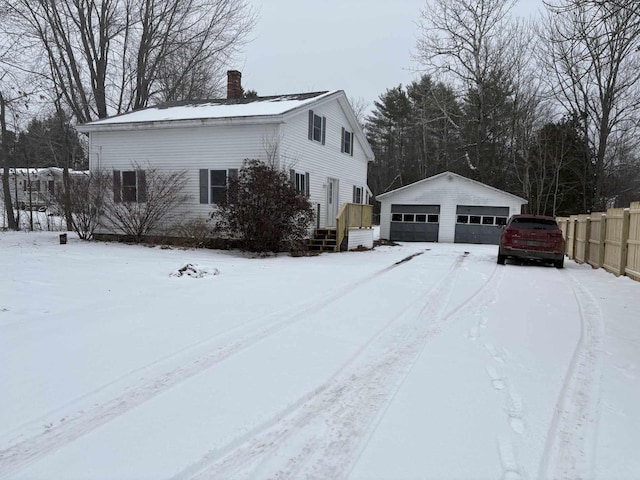 view of snow covered exterior featuring a garage and an outdoor structure