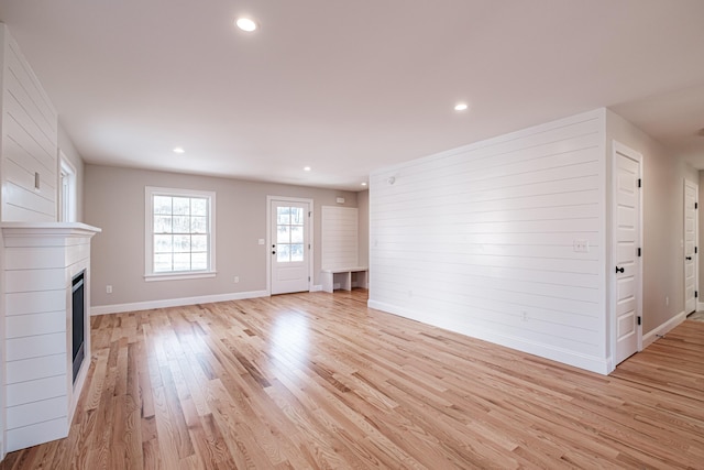 unfurnished living room featuring wood walls and light wood-type flooring