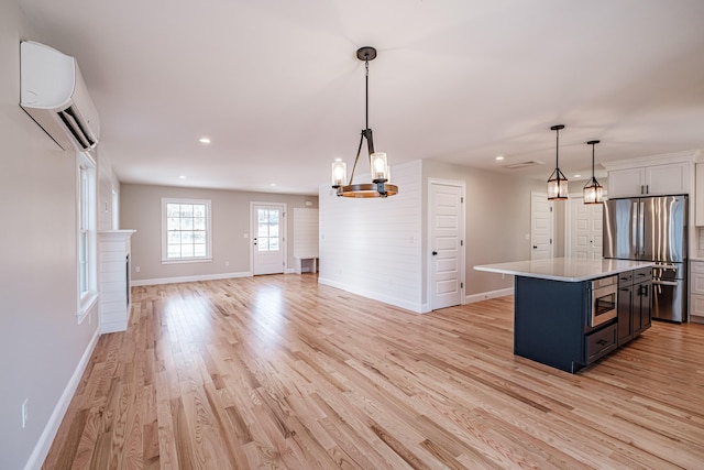 kitchen with stainless steel appliances, a wall mounted AC, a kitchen island, and hanging light fixtures