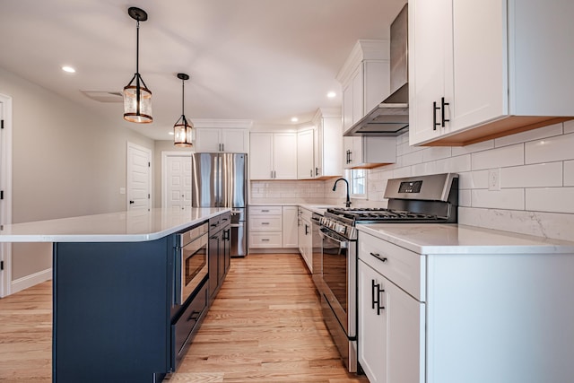 kitchen featuring appliances with stainless steel finishes, white cabinets, and wall chimney range hood