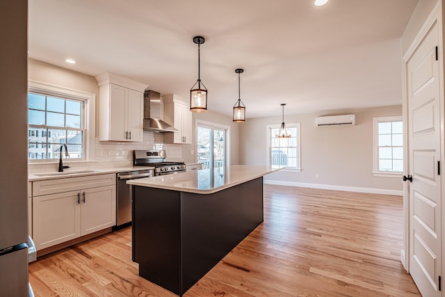 kitchen featuring sink, wall chimney exhaust hood, a kitchen island, a wall mounted air conditioner, and appliances with stainless steel finishes