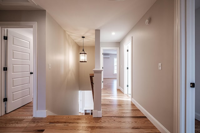 hallway with a wall mounted AC and light wood-type flooring