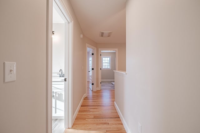 corridor featuring sink and light wood-type flooring