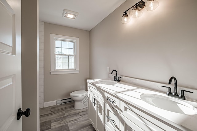 bathroom featuring toilet, vanity, and baseboard heating