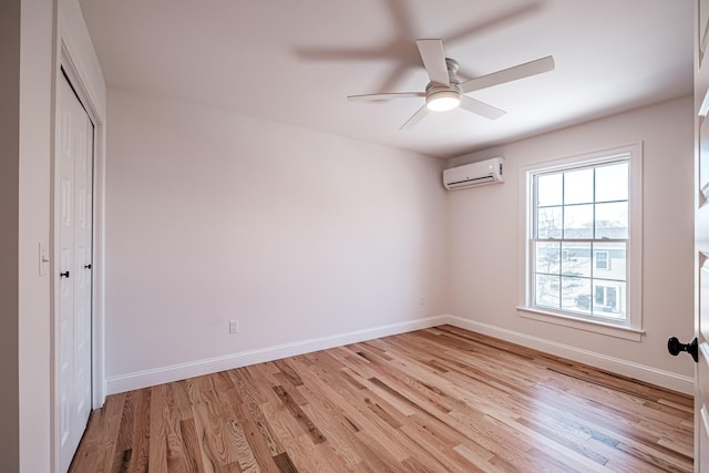 unfurnished bedroom featuring an AC wall unit, ceiling fan, light hardwood / wood-style floors, and a closet