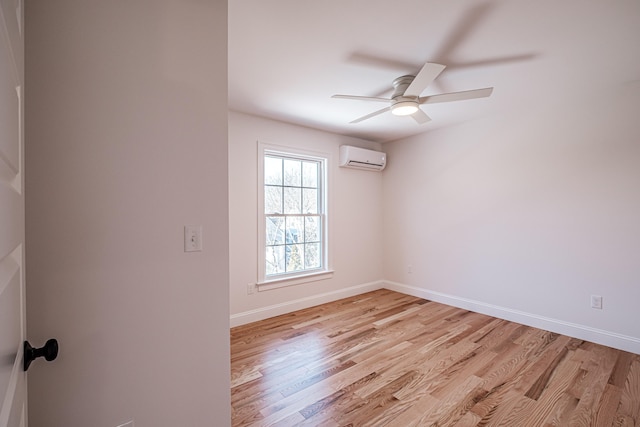 spare room featuring a wall unit AC, ceiling fan, and light hardwood / wood-style floors