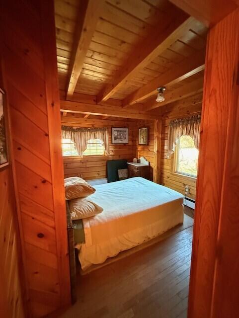 55 Brown Rd, Oakfield, ME 04763 - bedroom featuring wood ceiling, baseboard heating, wooden walls, hardwood / wood-style flooring, and beam ceiling