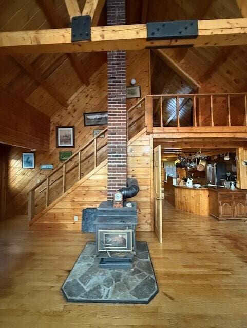 55 Brown Rd, Oakfield, ME 04763 - living room featuring high vaulted ceiling, wood walls, a wood stove, hardwood / wood-style flooring, and beam ceiling