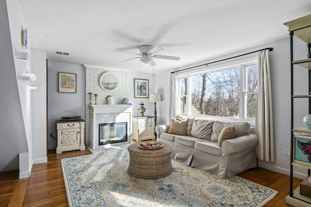 living room featuring a fireplace, ceiling fan, and dark hardwood / wood-style floors