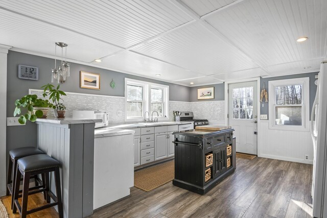 kitchen featuring white appliances, a breakfast bar area, a center island, dark wood-type flooring, and backsplash