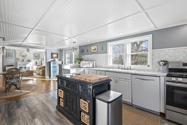 kitchen with white appliances, decorative backsplash, white cabinets, a fireplace, and sink