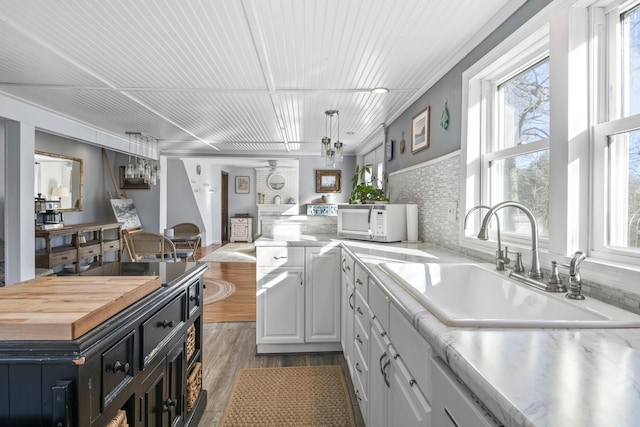 kitchen with wooden ceiling, hardwood / wood-style flooring, white cabinets, sink, and butcher block counters