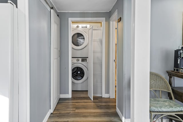 laundry room featuring dark hardwood / wood-style flooring, a barn door, and stacked washer / dryer