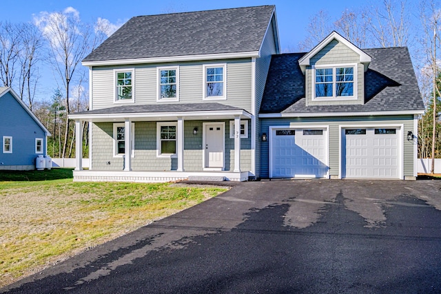 view of front facade featuring covered porch, a front yard, and a garage