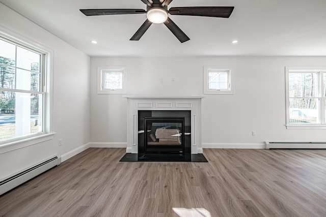 unfurnished living room featuring a wealth of natural light, light wood-type flooring, and a baseboard radiator