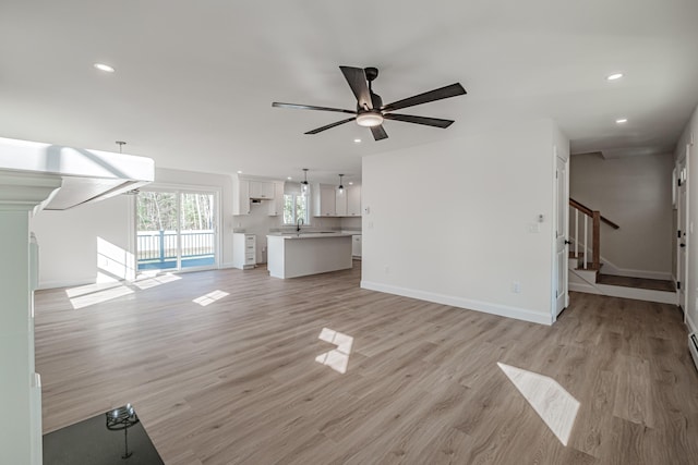 unfurnished living room with light wood-type flooring, ceiling fan, and sink