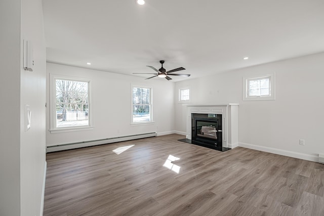 unfurnished living room with light hardwood / wood-style floors, ceiling fan, plenty of natural light, and a baseboard heating unit