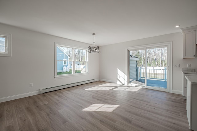 unfurnished dining area with light hardwood / wood-style flooring, an inviting chandelier, and a baseboard heating unit