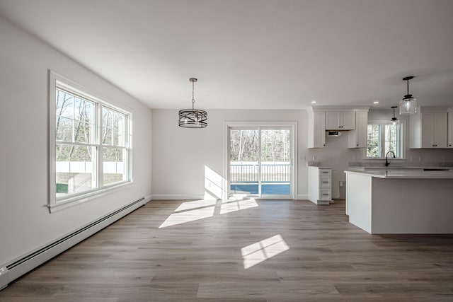 kitchen with white cabinets, hanging light fixtures, light wood-type flooring, and a baseboard radiator