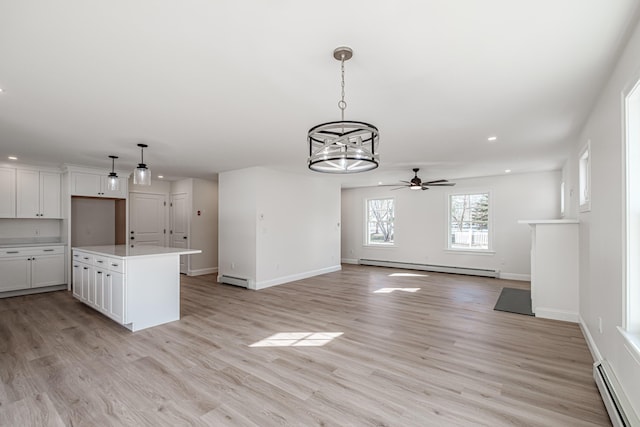 kitchen featuring white cabinetry, a center island, a baseboard radiator, and decorative light fixtures