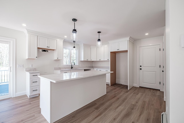 kitchen with a kitchen island, white cabinets, light wood-type flooring, and sink