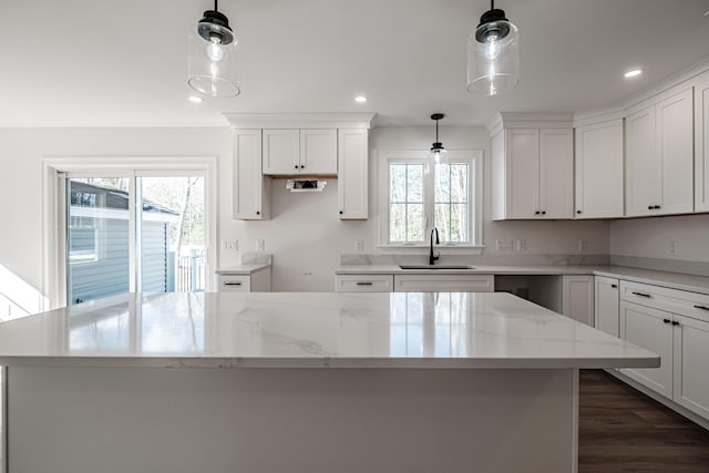 kitchen featuring sink, a healthy amount of sunlight, pendant lighting, and light stone counters