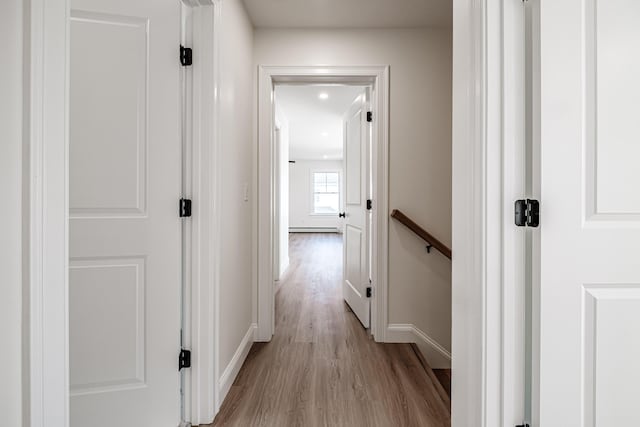 hallway with light wood-type flooring and a baseboard radiator