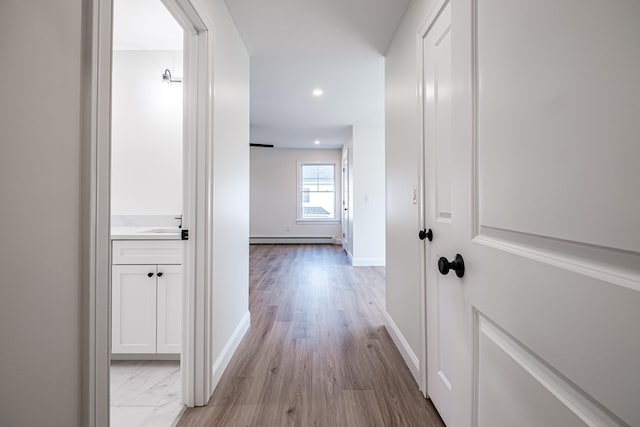 hall with baseboard heating and light wood-type flooring