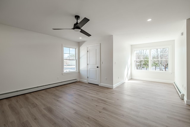 interior space featuring ceiling fan, a baseboard radiator, light hardwood / wood-style floors, and multiple windows