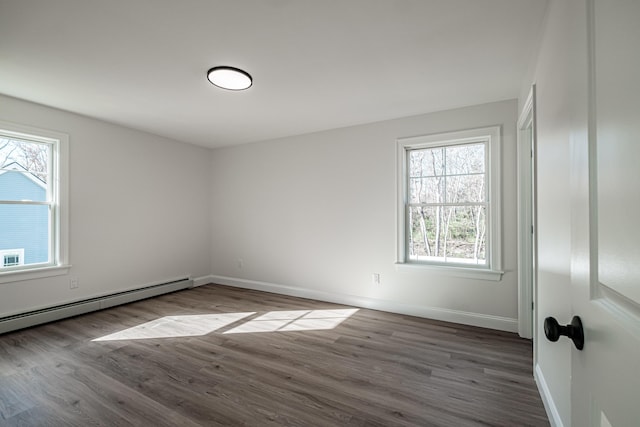 unfurnished room with baseboard heating, hardwood / wood-style floors, and a healthy amount of sunlight