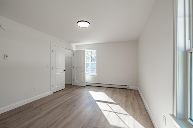 empty room featuring a baseboard heating unit and light wood-type flooring