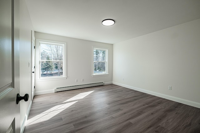 empty room with light hardwood / wood-style floors, a baseboard heating unit, and a wealth of natural light