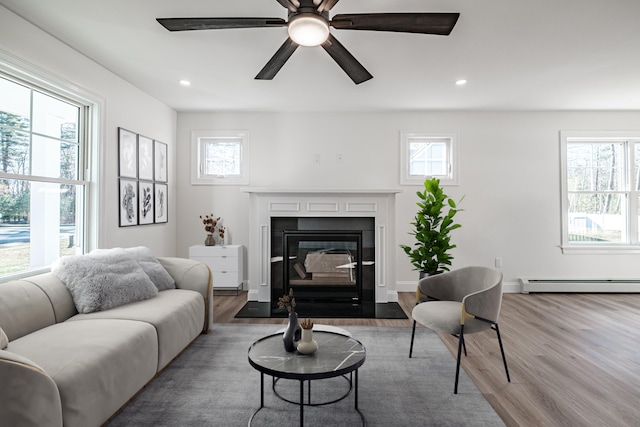 living room featuring ceiling fan, baseboard heating, and hardwood / wood-style flooring