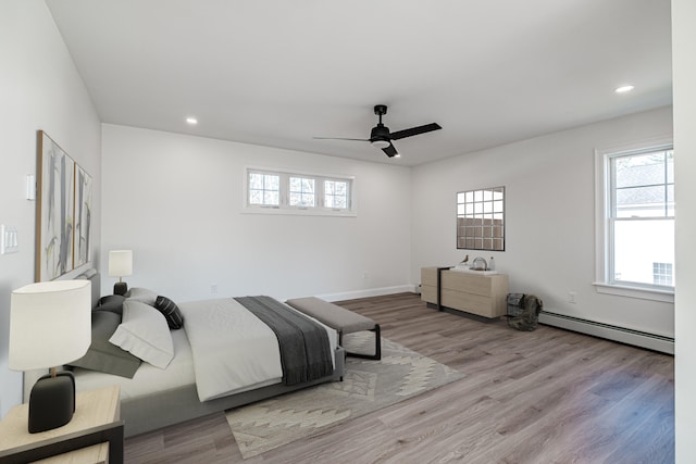 bedroom featuring a baseboard heating unit, ceiling fan, and light wood-type flooring