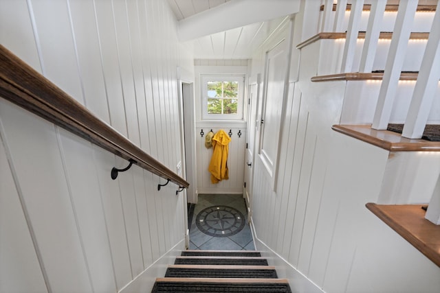 stairs featuring tile patterned flooring and wooden walls