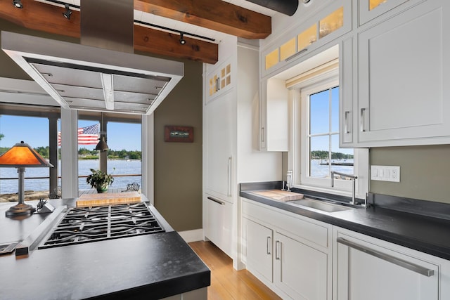 kitchen with white cabinetry, beamed ceiling, a water view, cooktop, and light hardwood / wood-style flooring