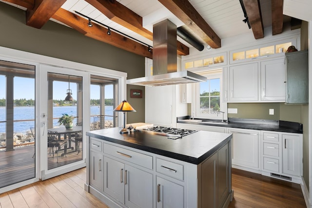 kitchen featuring a center island, white cabinetry, island range hood, and a water view