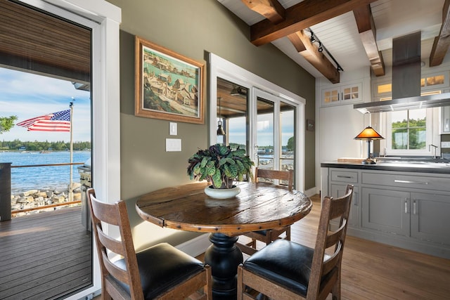 dining room with beam ceiling, a water view, wooden ceiling, and wood-type flooring