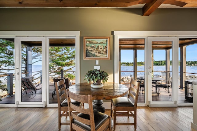 dining area featuring a wealth of natural light, beamed ceiling, and a water view