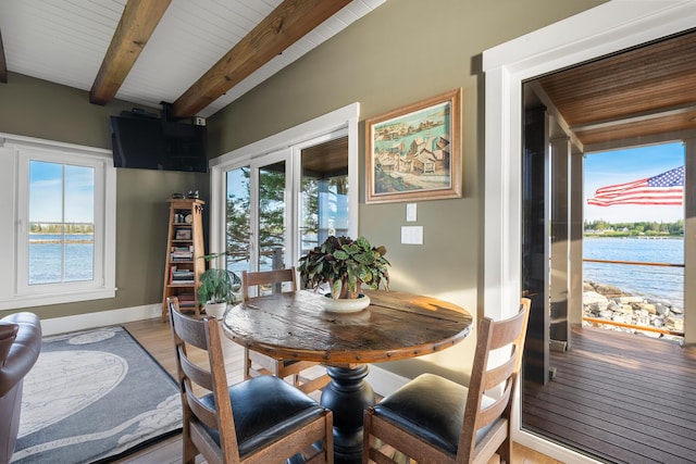 dining space with wood ceiling, light wood-type flooring, beamed ceiling, and a water view