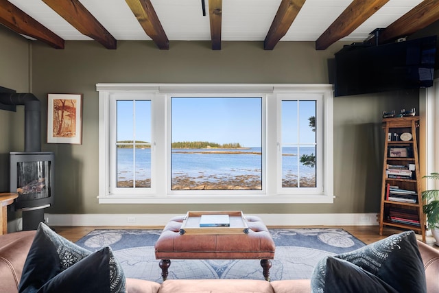 living room featuring beam ceiling, a wood stove, and wood-type flooring