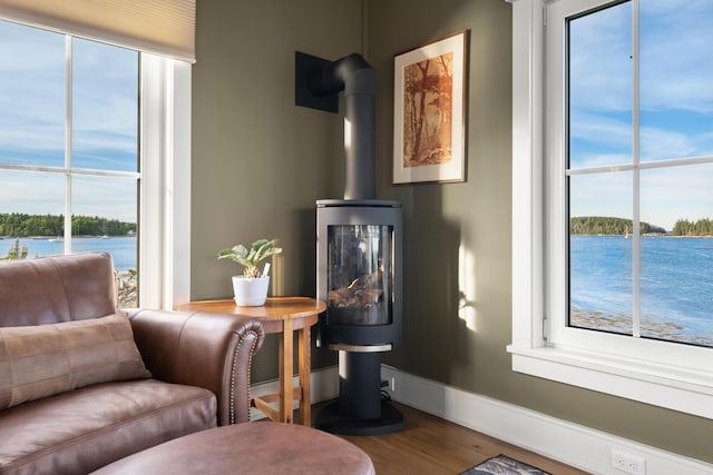 sitting room with hardwood / wood-style floors, a wood stove, and a water view