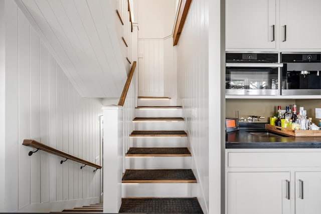 stairs featuring sink and wooden walls