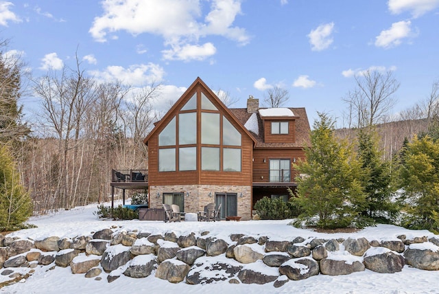 snow covered property featuring a wooden deck and a hot tub