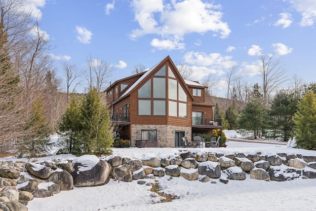 snow covered back of property featuring a wooden deck