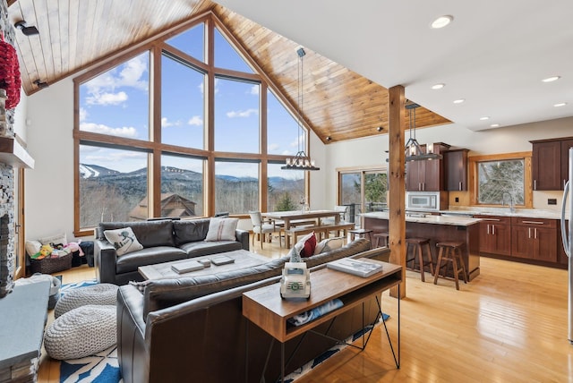 living room featuring lofted ceiling, a mountain view, light hardwood / wood-style flooring, wood ceiling, and a stone fireplace