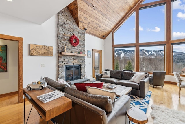 living room featuring light hardwood / wood-style floors, a mountain view, a stone fireplace, and high vaulted ceiling