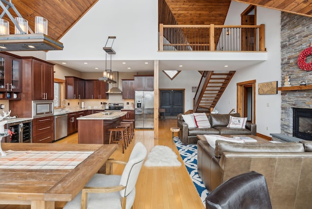 interior space featuring wood ceiling, light hardwood / wood-style floors, a fireplace, beverage cooler, and high vaulted ceiling