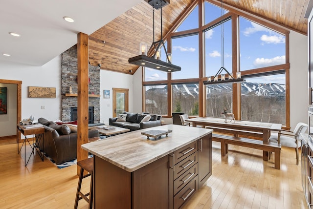 kitchen featuring a mountain view, a kitchen island, a stone fireplace, and a healthy amount of sunlight